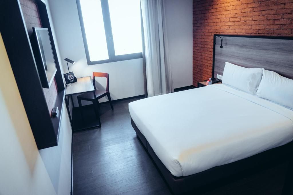 A hotel room with a bed, a desk, and a chair.