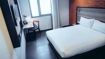 A hotel room with a bed, a desk, and a chair.