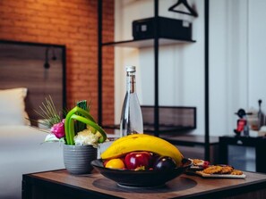 Une table à manger avec un saladier de fruits, une bouteille et un arrangement floral.
