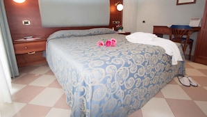Un dormitorio con una cama grande, una mesita de noche, un escritorio y una silla.