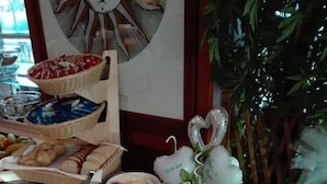 Una mesa de buffet con diferentes alimentos, como pasteles, frutas, y un reloj decorativo en la pared.