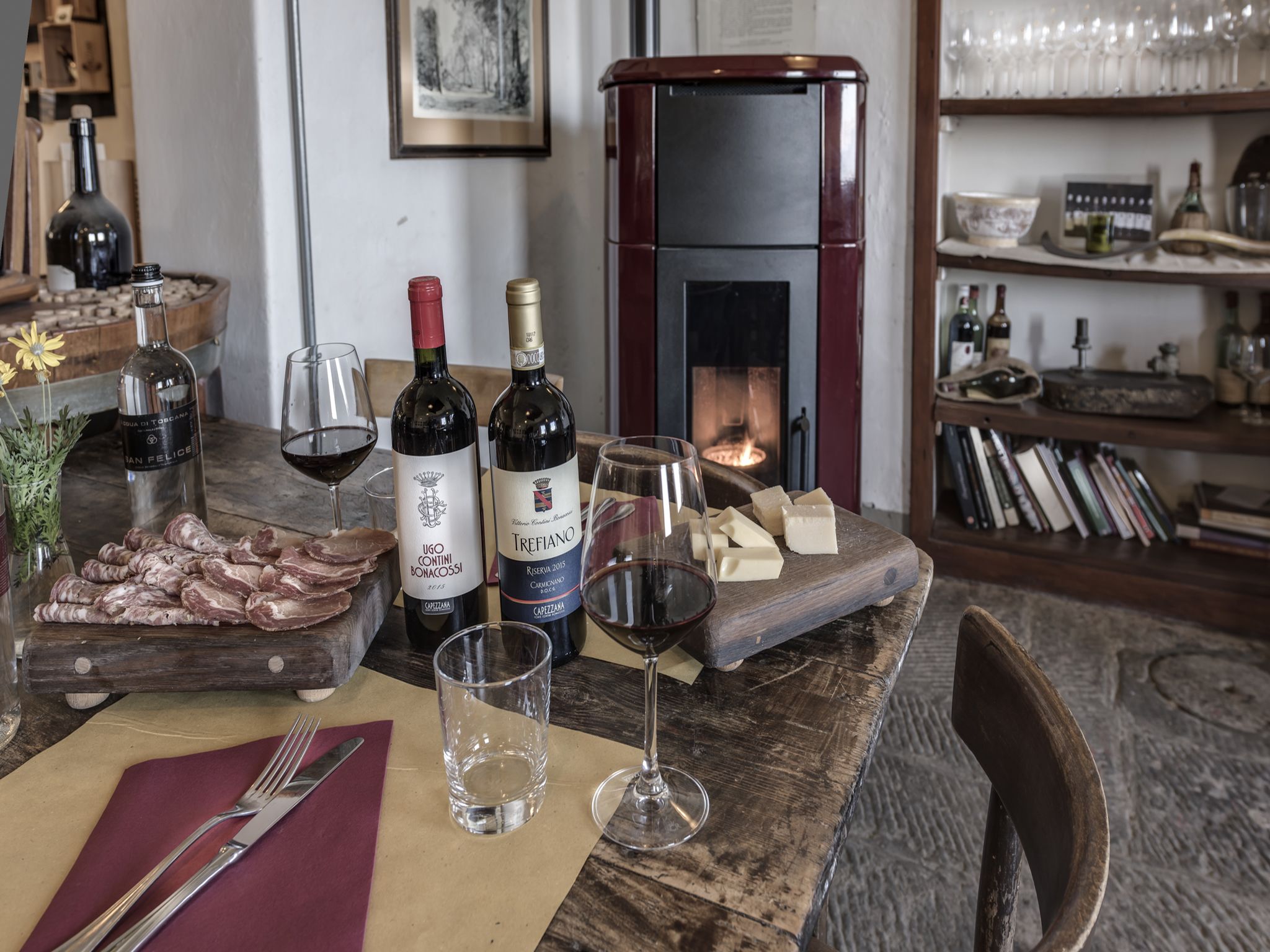 A wooden table with wine bottles, glasses, and a cheese board.