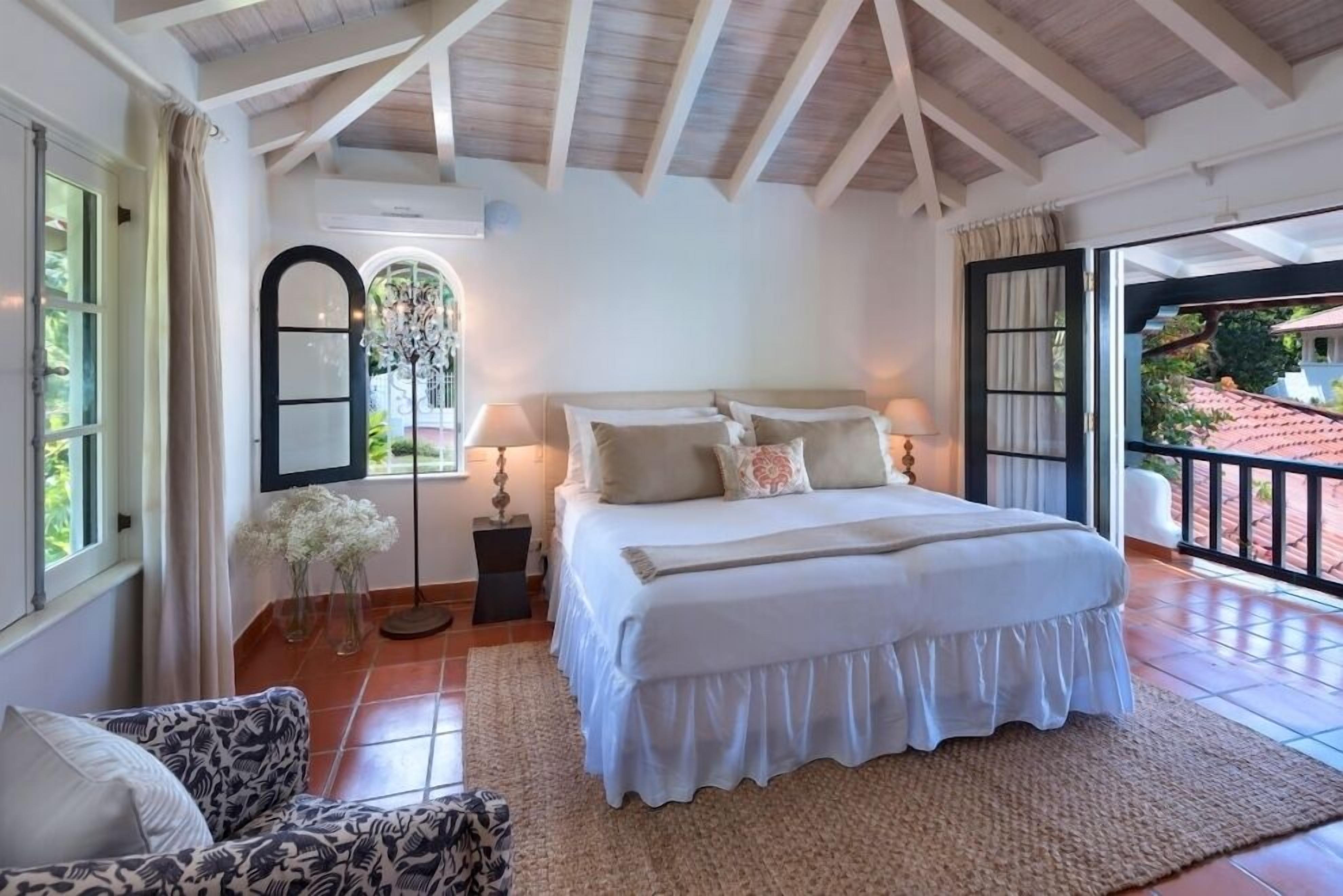 Une chambre à coucher avec un grand lit, un canapé, un lustre et une vue sur l’extérieur.