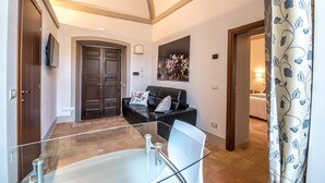 A modern living room with a glass coffee table, a black leather sofa, and a painting on the wall. - Suite Assisi (Assisi)