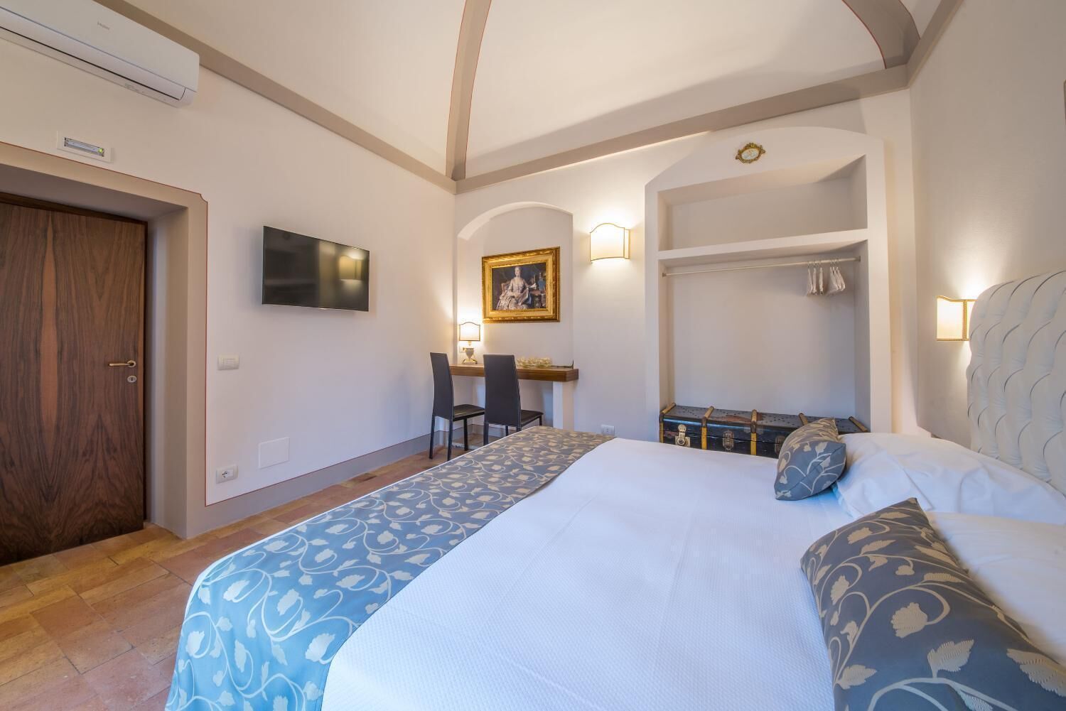 Habitación de hotel con cama, escritorio, silla y armario.