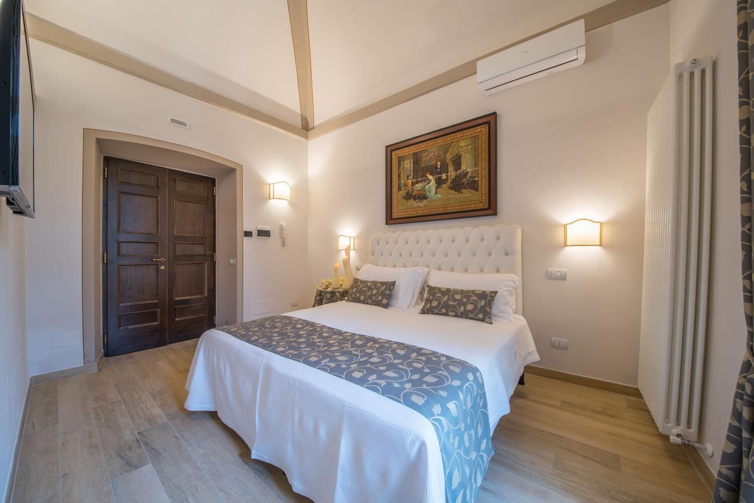 Una camera da letto con un letto grande, una porta in legno e un quadro appeso al muro.