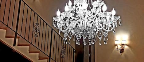 Uma escadaria imponente com um lustre de cristal e arandelas.