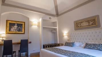 A bedroom with a large bed, a desk with chairs, and a painting on the wall.