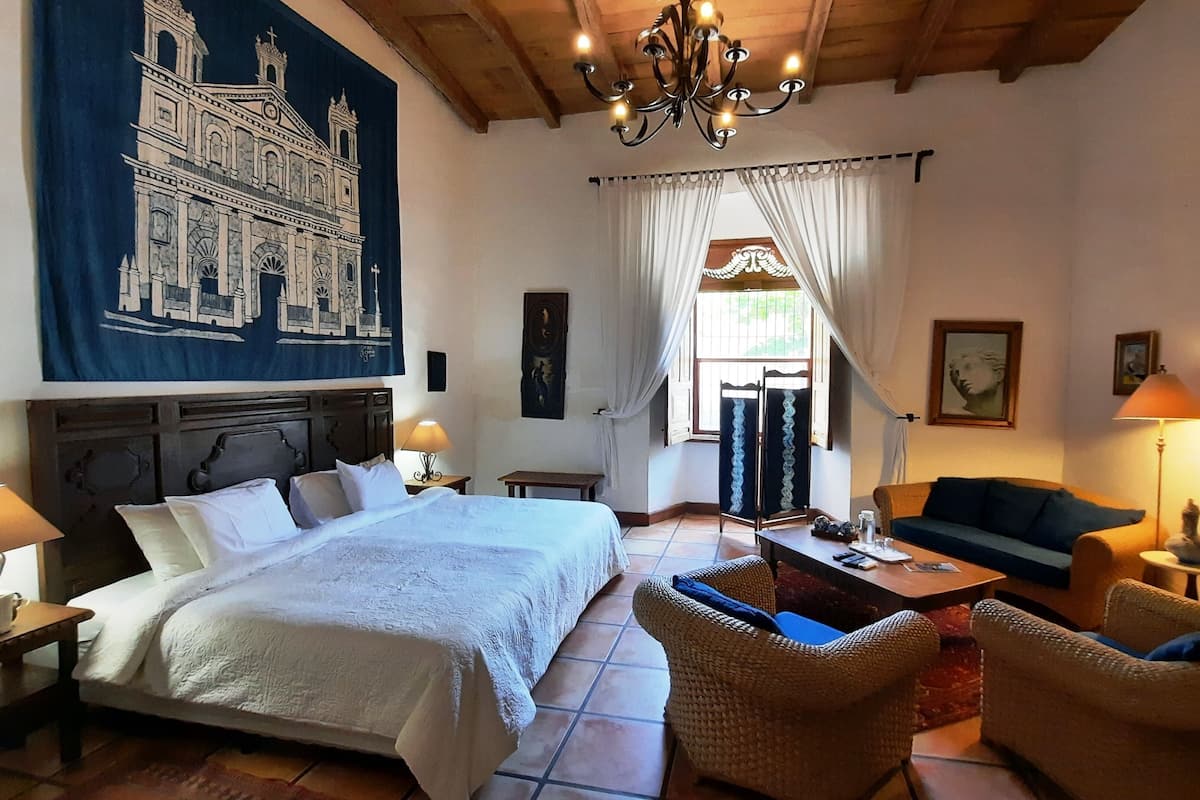 Ein Schlafzimmer mit einem großen Bett, einem Schlafsofa, einem Sessel, einem Tisch und einer Chandelier.