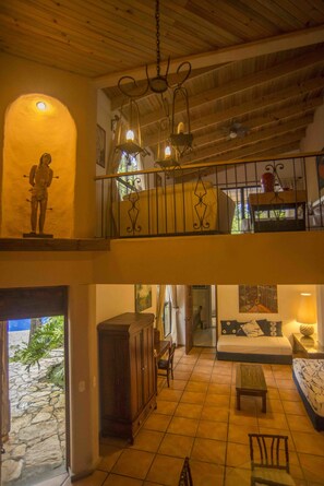 A multi-level interior with a staircase, a dining area, and a living room with a sofa and a coffee table.