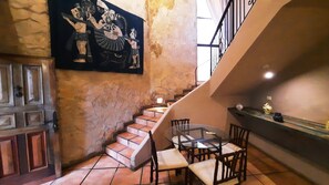 A dining area with a table and chairs, a staircase, and a mural on the wall.