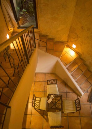 A staircase with a view of a dining area below, featuring a table and chairs.