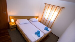 Habitación doble con dos camas, cada una con una mesita de noche, una lámpara y una ventana con cortinas.