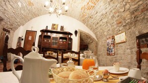 A rustic dining area with a stone wall, a wooden cabinet, and a chandelier. - B&B Mario Lupo (Bergamo)