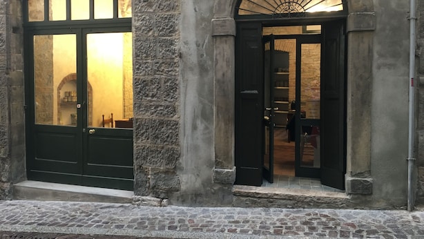 A stone building with two arched doorways, one leading to a room with a large window and the other to a room with a shelf and a door. - B&B Mario Lupo (Bergamo)