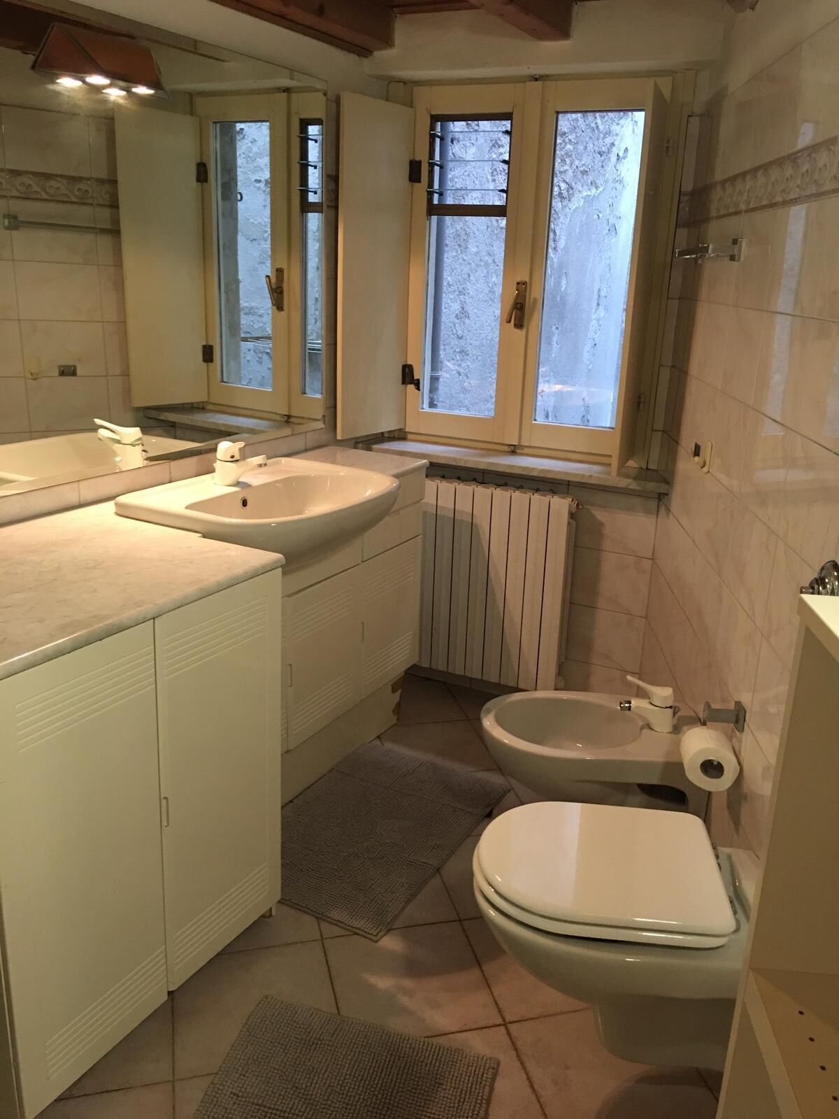 A compact bathroom with a bathtub, a sink, a toilet, and a window providing natural light.