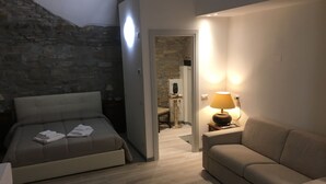 A bedroom with a bed, a sofa, a lamp, and a stone wall. - B&B Mario Lupo (Bergamo)