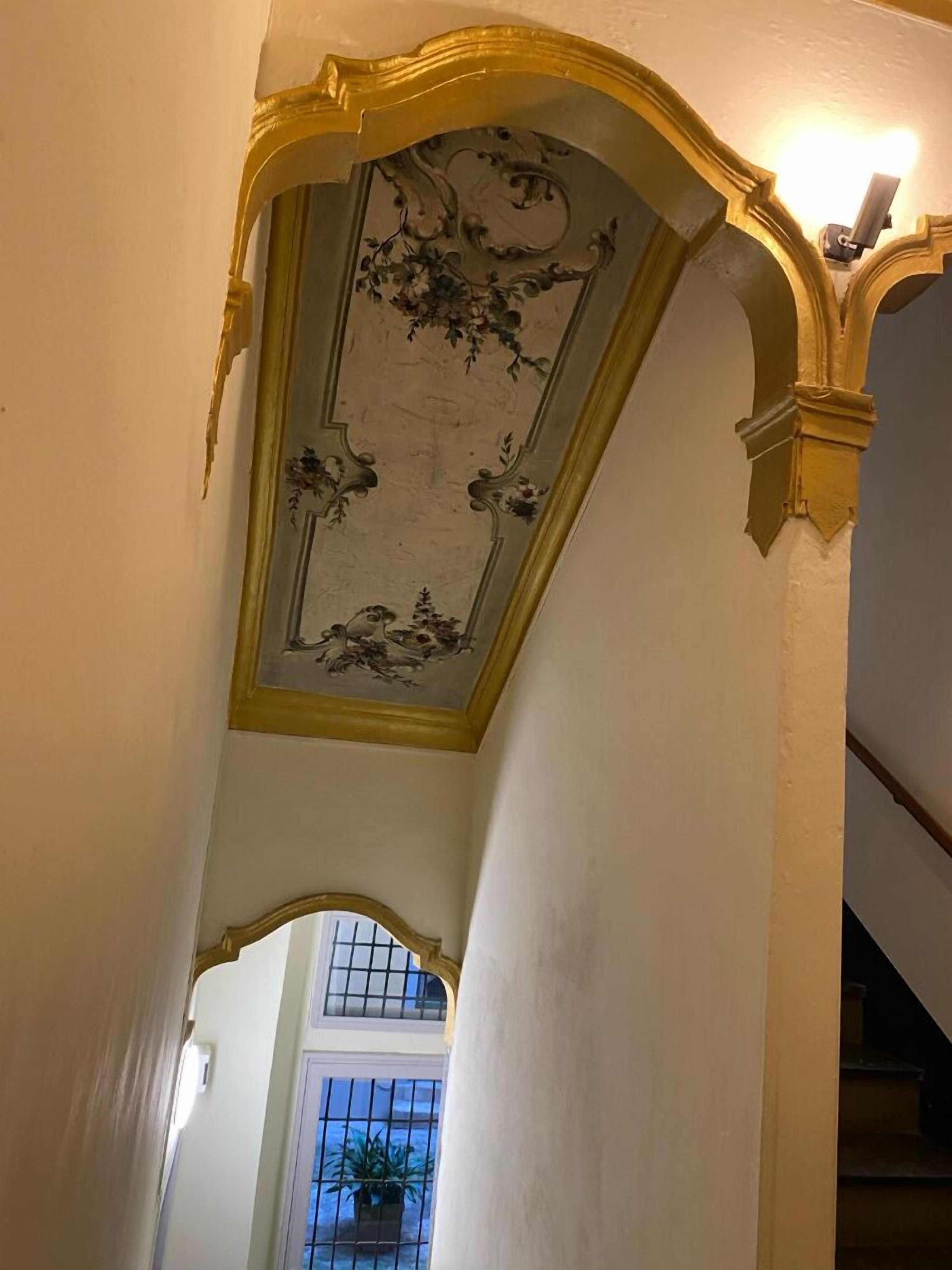 A staircase with ornate golden moldings and a decorative ceiling with floral patterns.