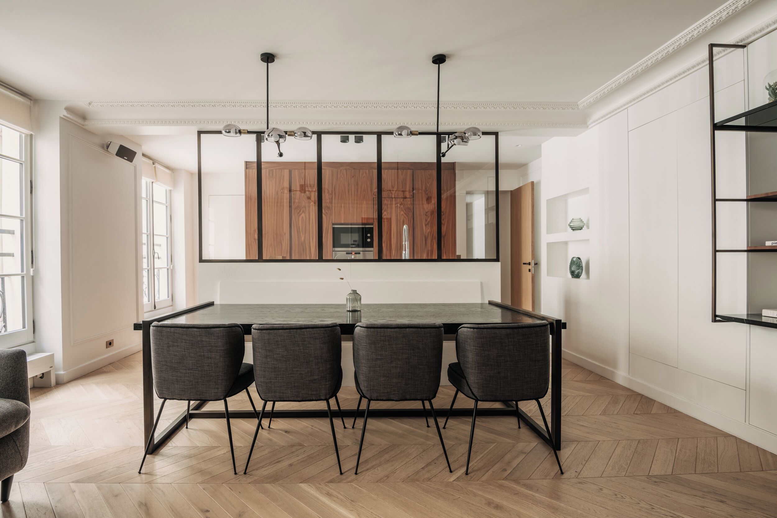 A modern kitchen with a large island, wooden cabinets, and a black-framed pendant light.