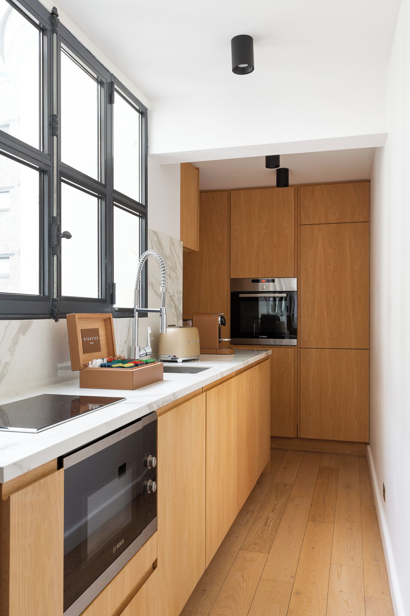A modern kitchen with wooden cabinets, a built-in oven, and a window with a view.