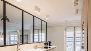 A modern kitchen with a large island, a double sink, and a large mirror. - HIGHSTAY - Luxury Serviced Apartments - Place Vendôme (Paris)
