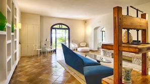 A spacious living area with a blue sofa, white chairs, and a wooden staircase. - Villa Amiela (Massa Lubrense)