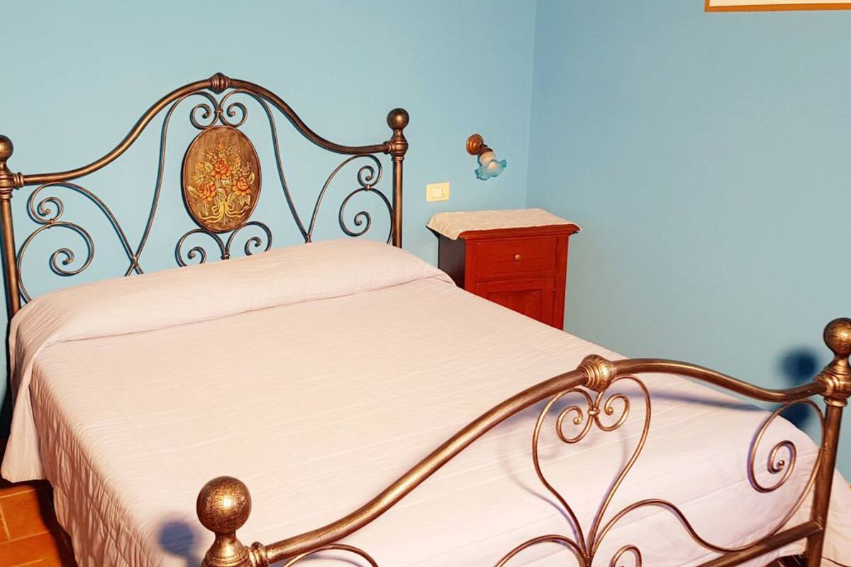 A bedroom with a metal bed frame, a wooden nightstand, and a red bedside table.