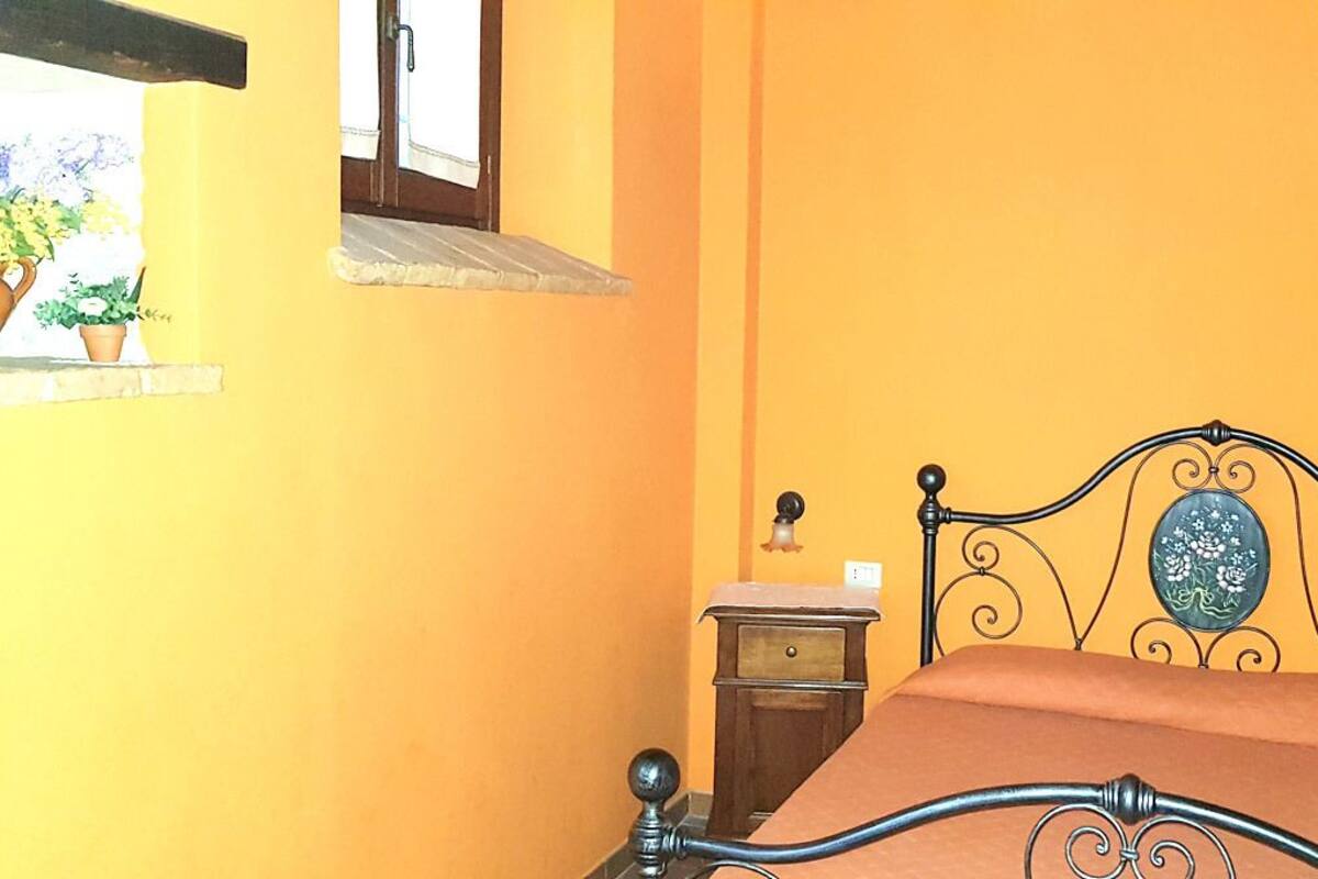 A bedroom with a bed, a nightstand, a dresser, and a window with a view of the outside.