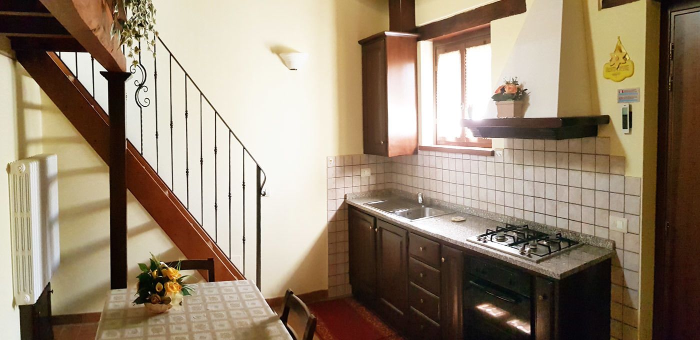 A kitchen with a tiled backsplash, a gas stove, and a window above the sink.