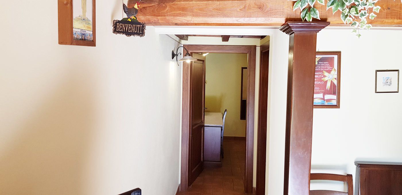 A hallway with a wooden ceiling, a sign reading "BENVENUTI", and a framed picture on the wall.