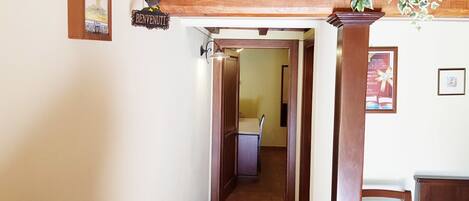 A hallway with a wooden ceiling, a sign reading "BENVENUTI", and a framed picture on the wall.