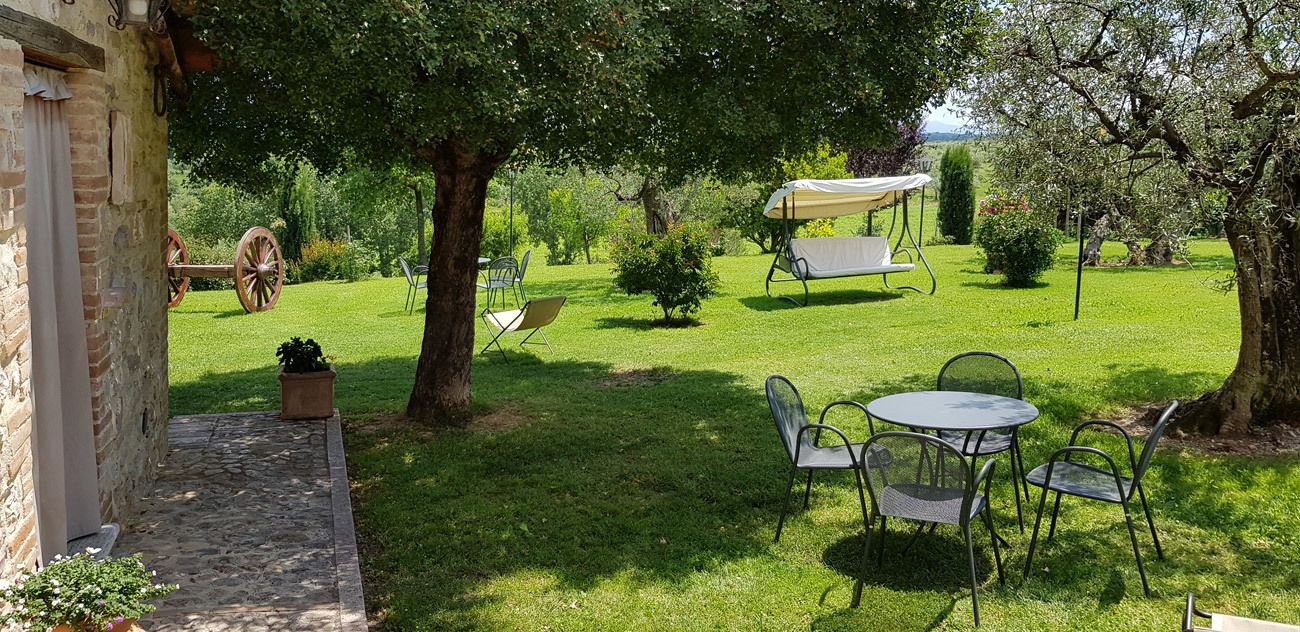 A garden with a stone pathway, a table with chairs, and a swing set.