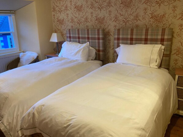 A hotel room with two beds, a nightstand, a lamp, and a window with a view. - Drovers Bed & Breakfast (Llandovery)