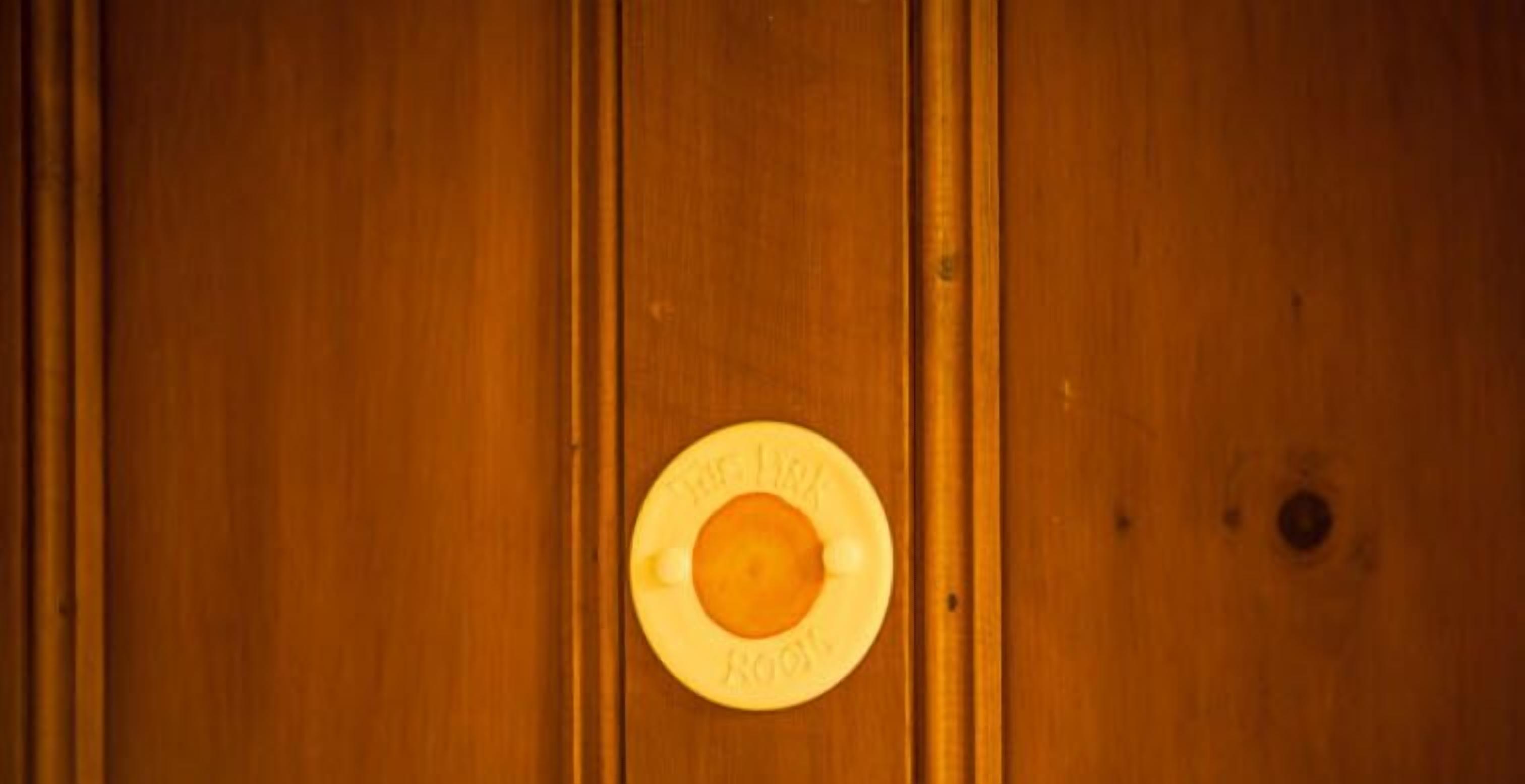 A wooden door with a circular handle and a plaque that reads "The Hotel Room."