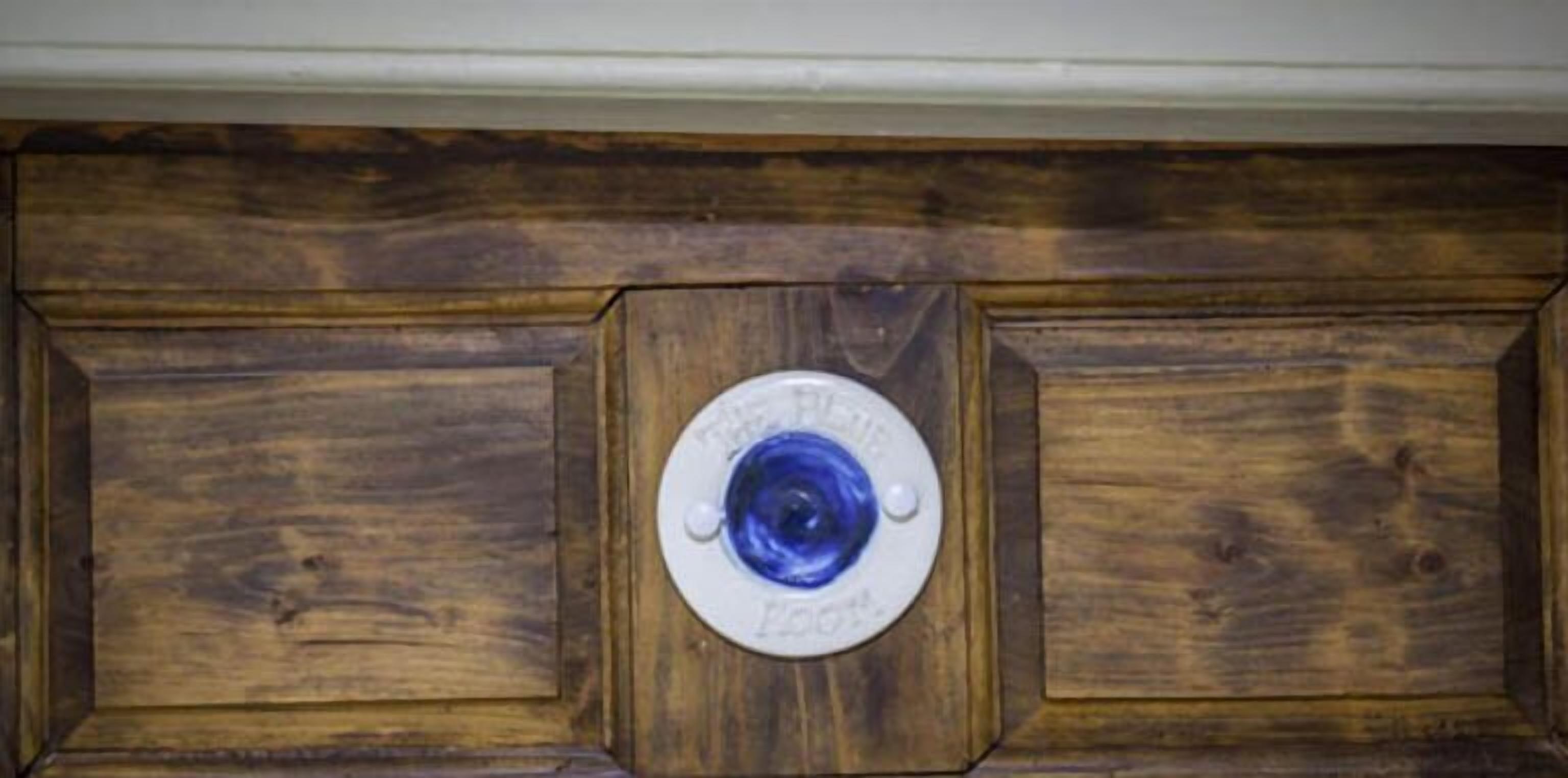 Un panneau en bois sur lequel on aperçoit un objet circulaire qui ressemble à un luminaire ou à un élément décoratif.