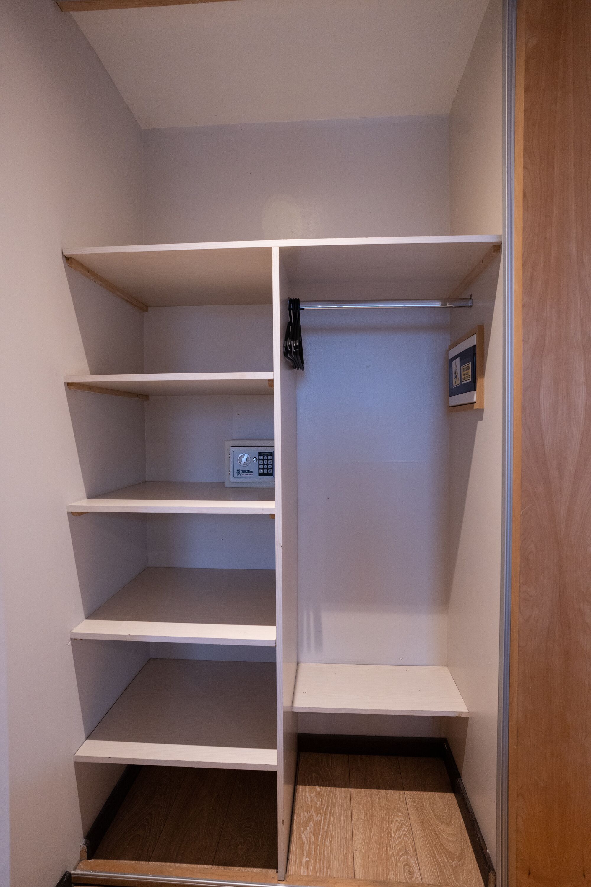 A walk-in closet with multiple shelves and a small safe.