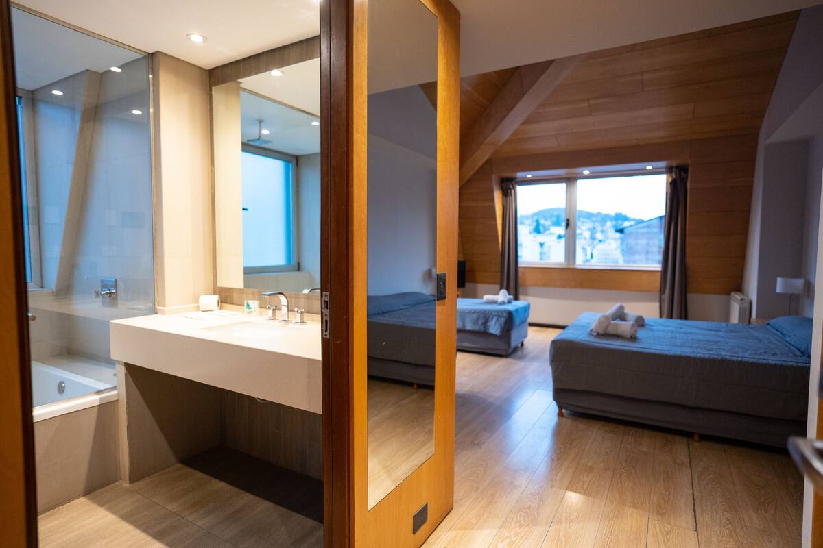 Un dormitorio moderno con un ventanal grande, techo de madera y cama empotrada.