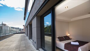A modern hotel room with a large bed, a glass door leading to a balcony, and a city view. - Hotel Bariloche Suites (San Carlos de Bariloche)