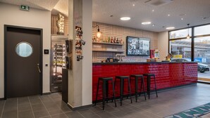A bar area with a red brick counter, stools, and a wall-mounted TV displaying photos.