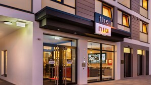 A modern hotel entrance with glass doors, a sign reading "the niu," and a visible reception area inside.
