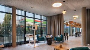 A spacious lobby with large windows, teal chairs, a coffee table, and a reception desk.