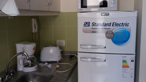 Een kleine keuken met een inbouwkoelkast, een magnetron, een koffiezetapparaat en een broodrooster.