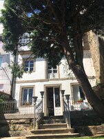 Un edificio de dos pisos con una escalera de piedra que lleva a una puerta con una reja de hierro decorativa.