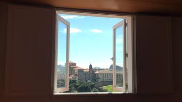 Una habitación con un amplio ventanal que ofrece vistas a un complejo de edificios históricos.