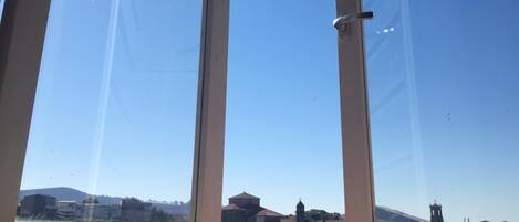 A clear sky through a window with a view of buildings and a tower in the distance.