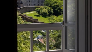 A room with a large window overlooking a courtyard with a building and greenery. - Pensión O Xardin de Julia (Santiago de Compostela)