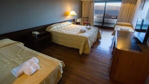 Ett hotellrum med två sängar, ett skrivbord, en stol och ett stort fönster med utsikt.