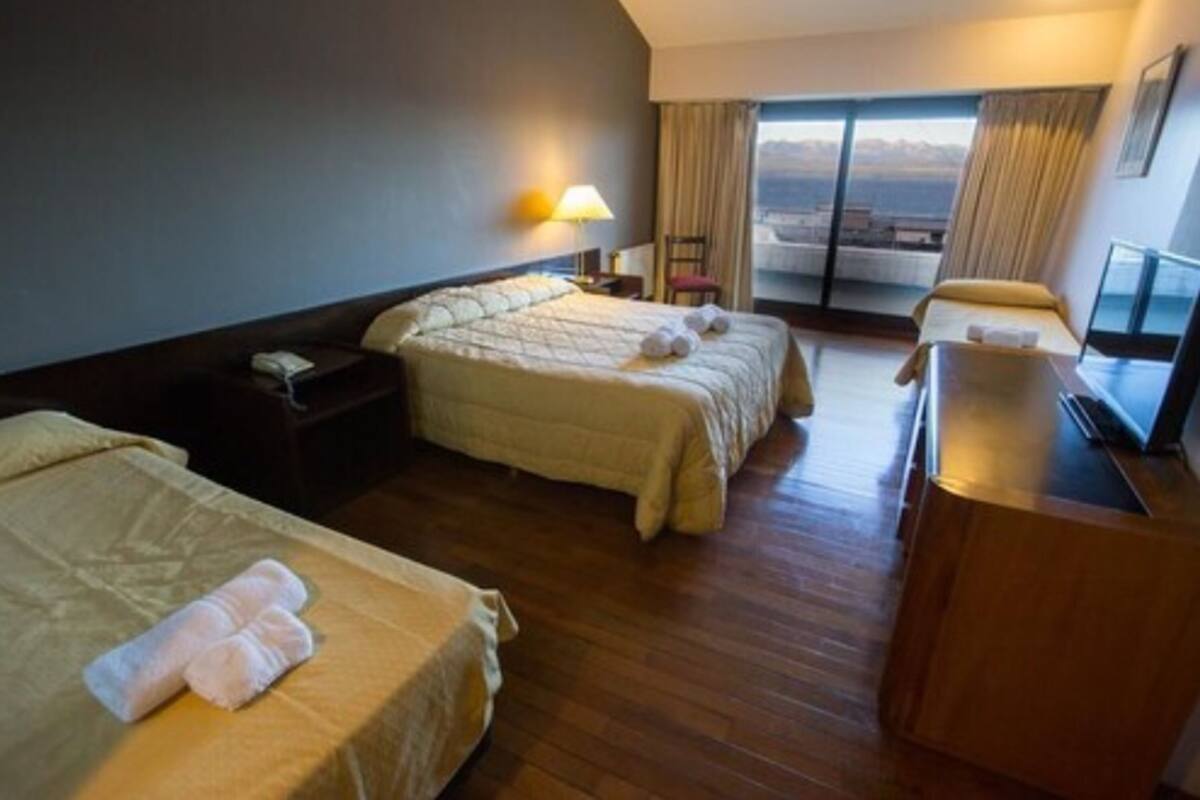 Une chambre d’hôtel avec deux lits, un bureau, une chaise et une grande fenêtre donnant sur un paysage agréable.