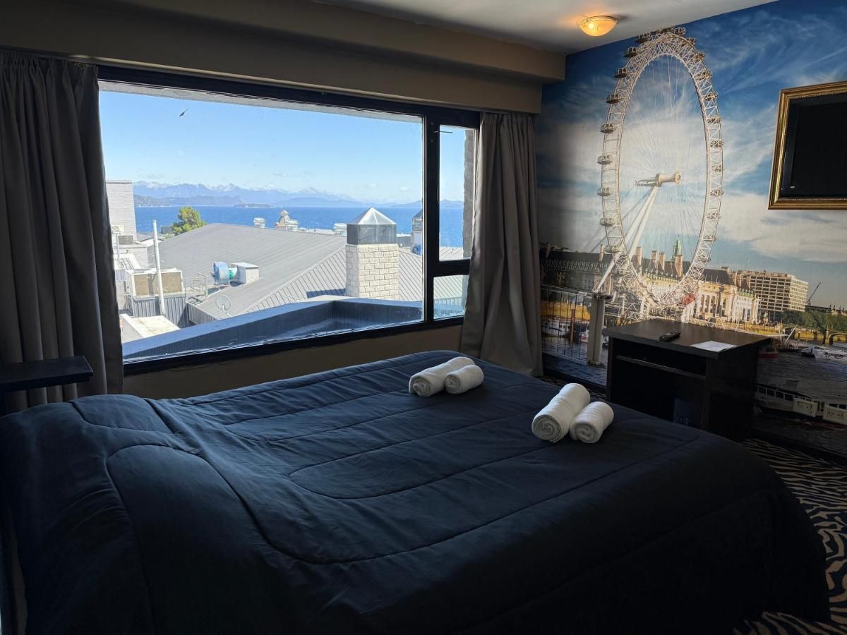 A hotel room with a large bed, a desk, and a view of a Ferris wheel.