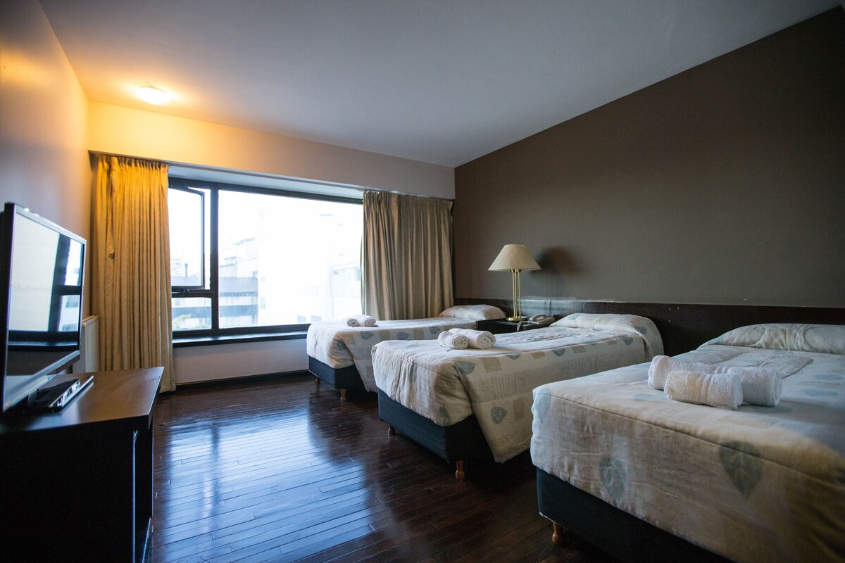Une chambre d’hôtel avec deux lits, une télévision et une fenêtre avec des rideaux.